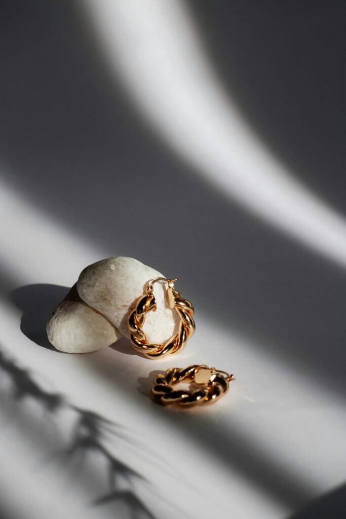 Twisted gold hoop earrings on white stones